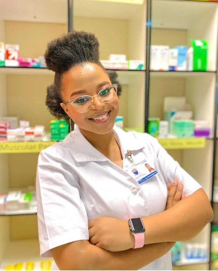 A pharmacist standing in front of the dispensing shelves